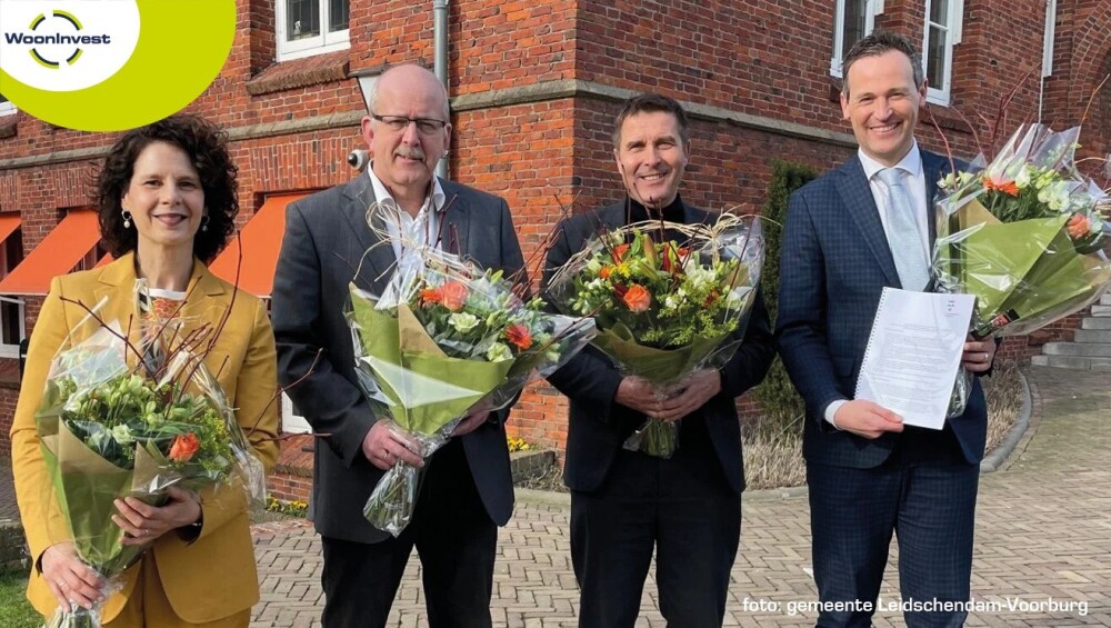 Stakeholders gemeente en WoonInvest met bos bloemen in de hand na ondertekening convenant gebruik warmtenet